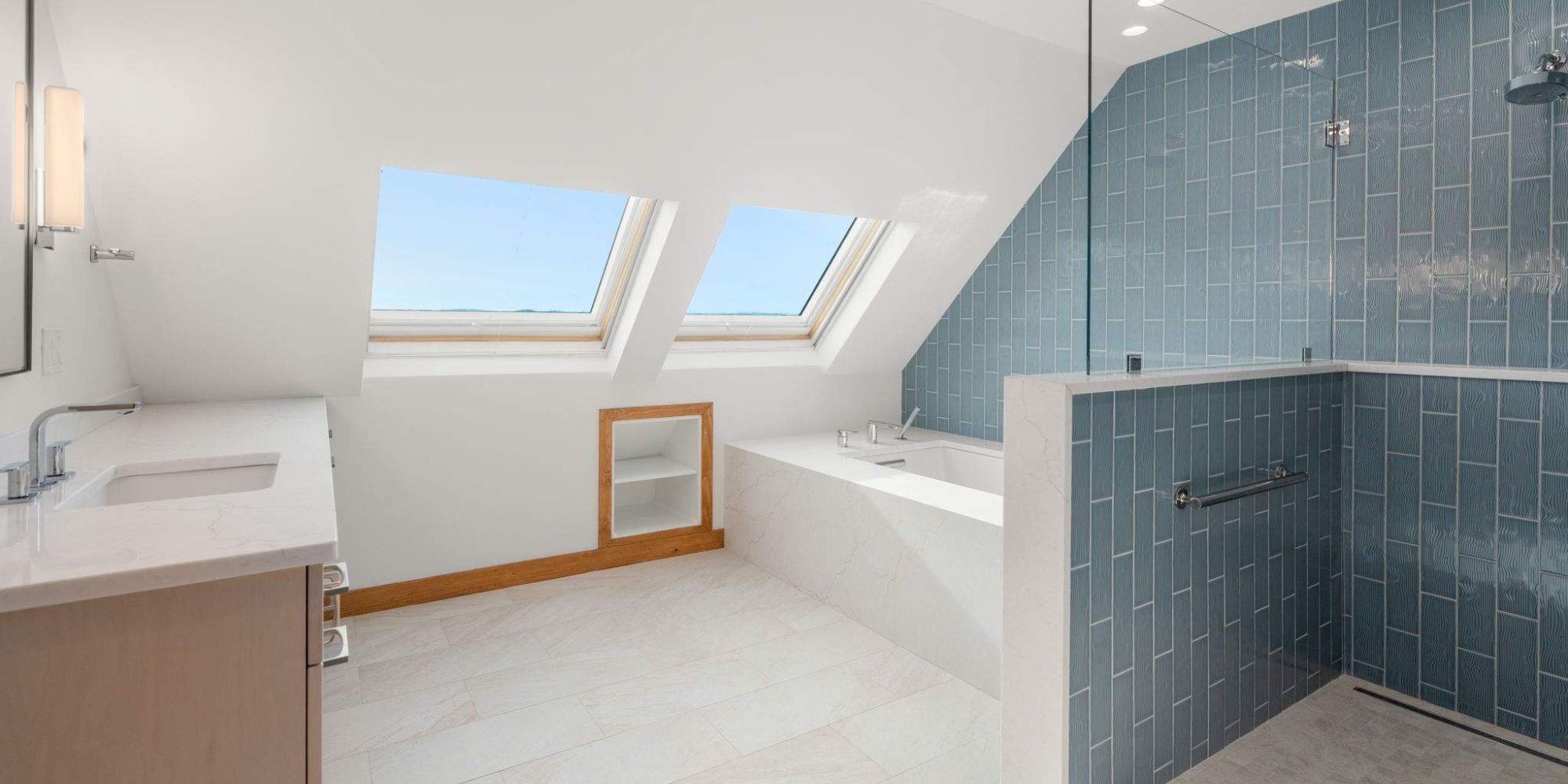 Remodeled bathroom with a built-in soaking tub, slanted ceiling, and blue tile on one wall by Gilmore Building Co. in Stow, MA
