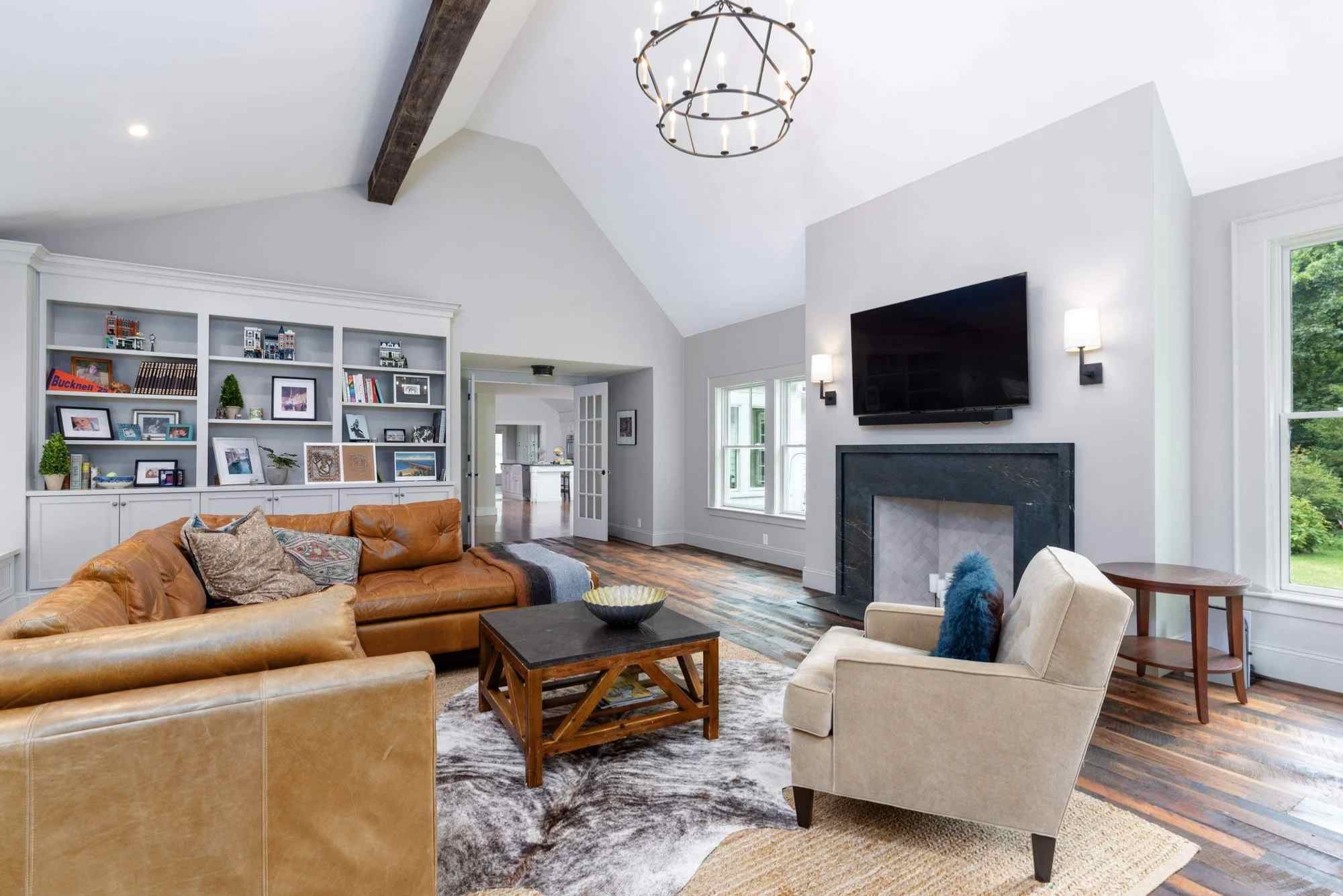 A custom living room addition with a fireplace, built-in shelves and cabinets, a vaulted ceiling, and hardwood floors by Gilmore Building Co.