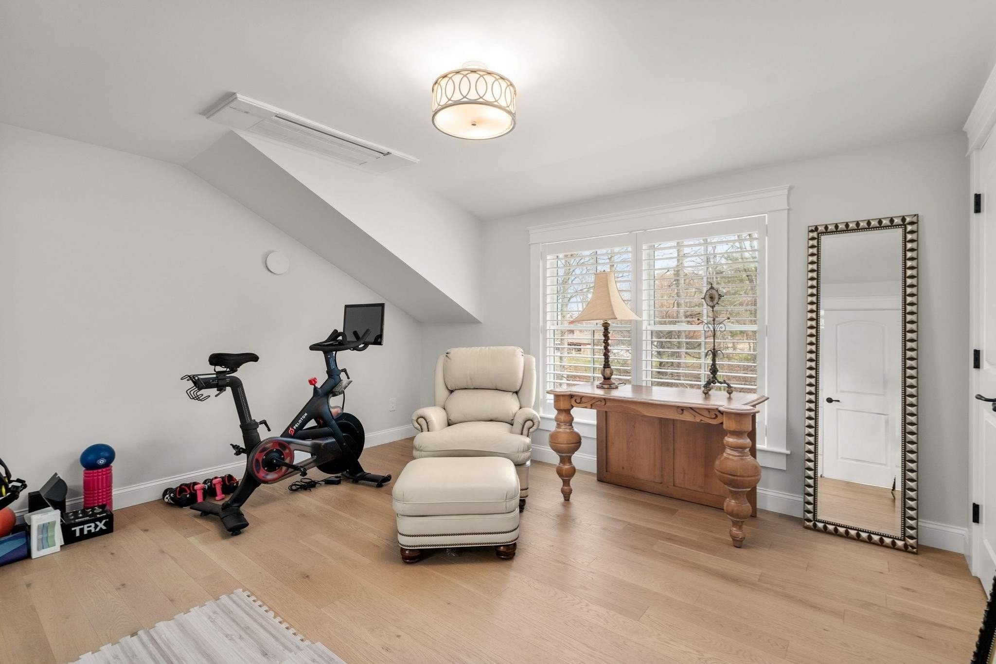 A specialty recreation room in a custom home by Gilmore Building Co. with hardwood flooring, large window, and stationary bike i