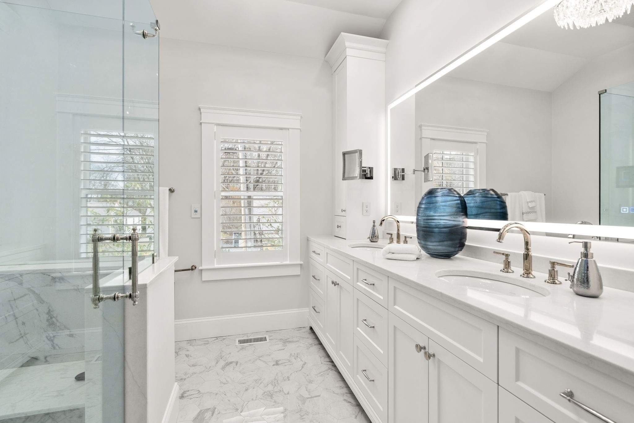 Bathroom in a whole home remodel with a dual-sink vanity, glass walk-in shower, and a large mirror by Gilmore Building Co. in Gr