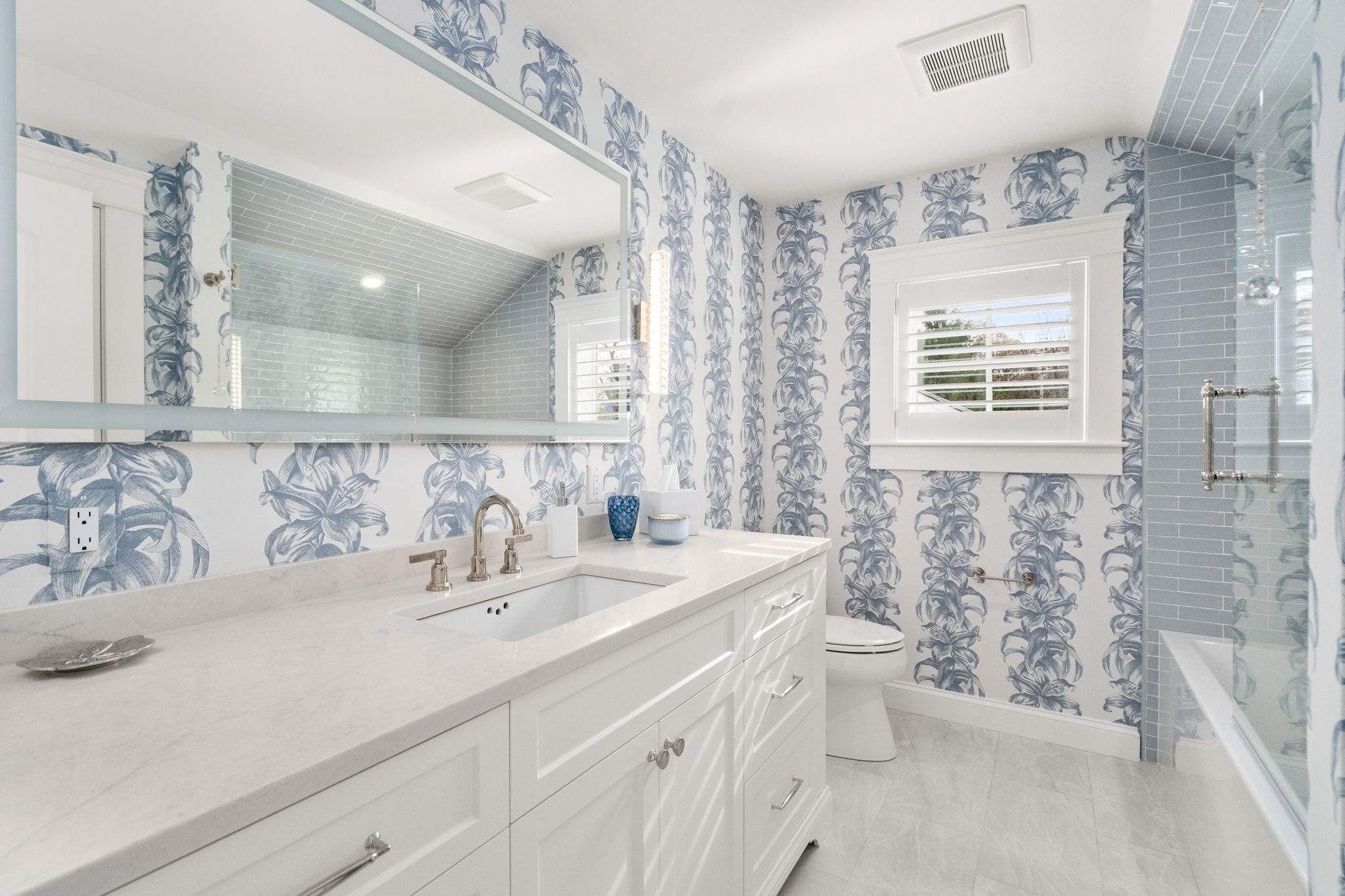 Custom bathroom in Grafton, MA with a custom vanity and blue and white flower-patterned wallpaper by Gilmore Building Co