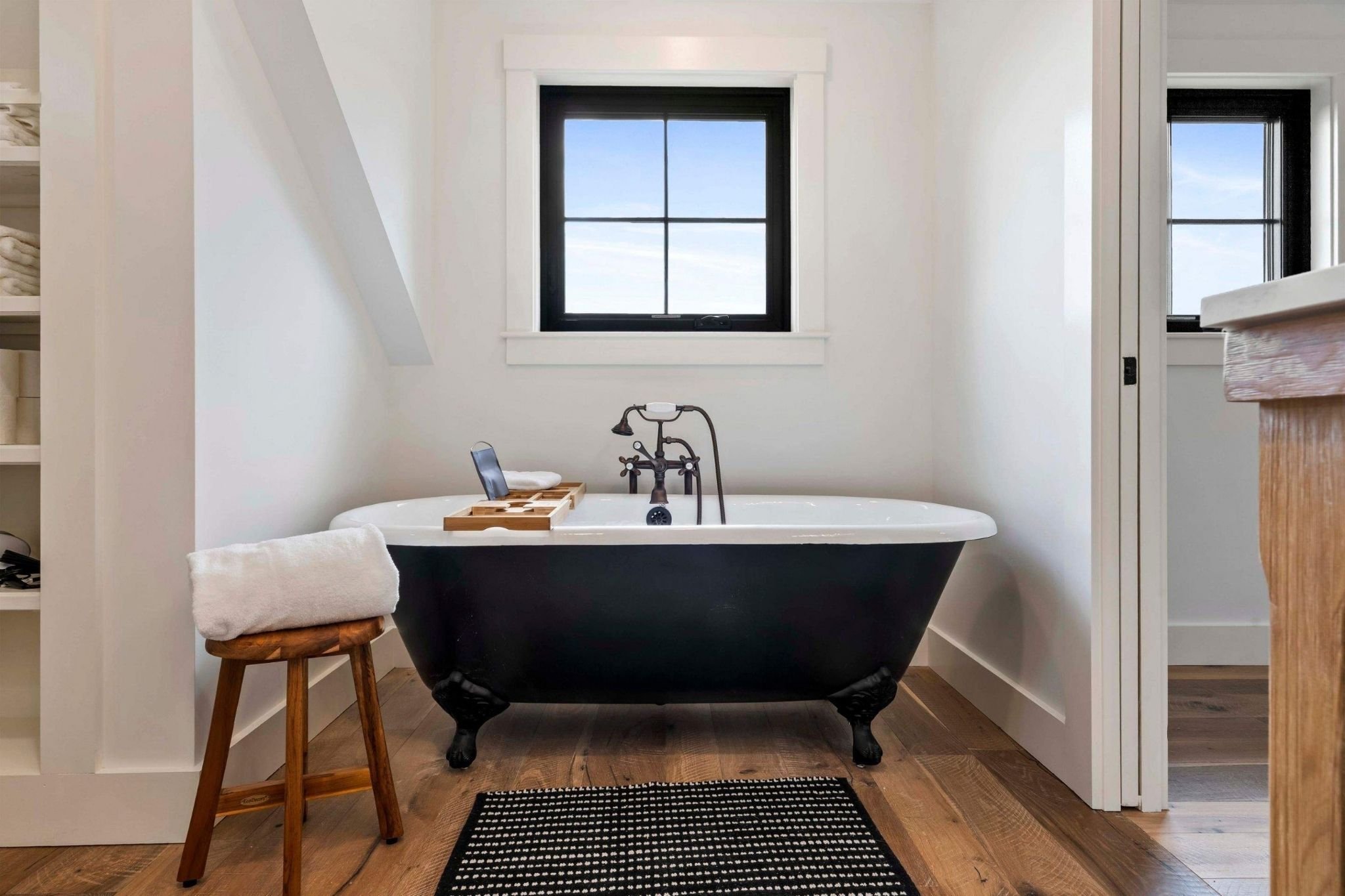 Custom bathroom in a Central Massachusetts whole home remodel with a standalone soaking tub with a window above by Gilmore Build