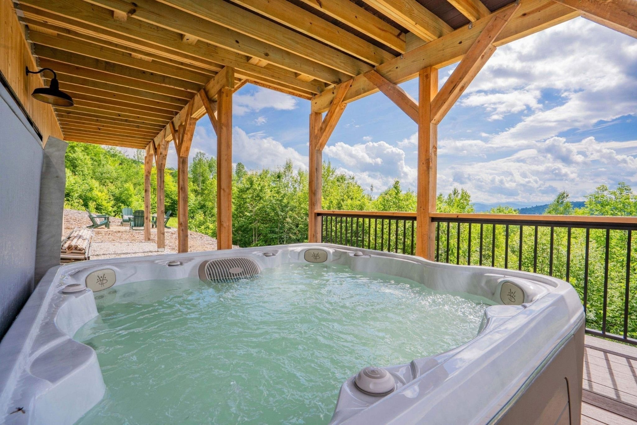 Patio with a hot tub under a second-floor deck on a custom home by Gilmore Building Co. in Central Massachusetts