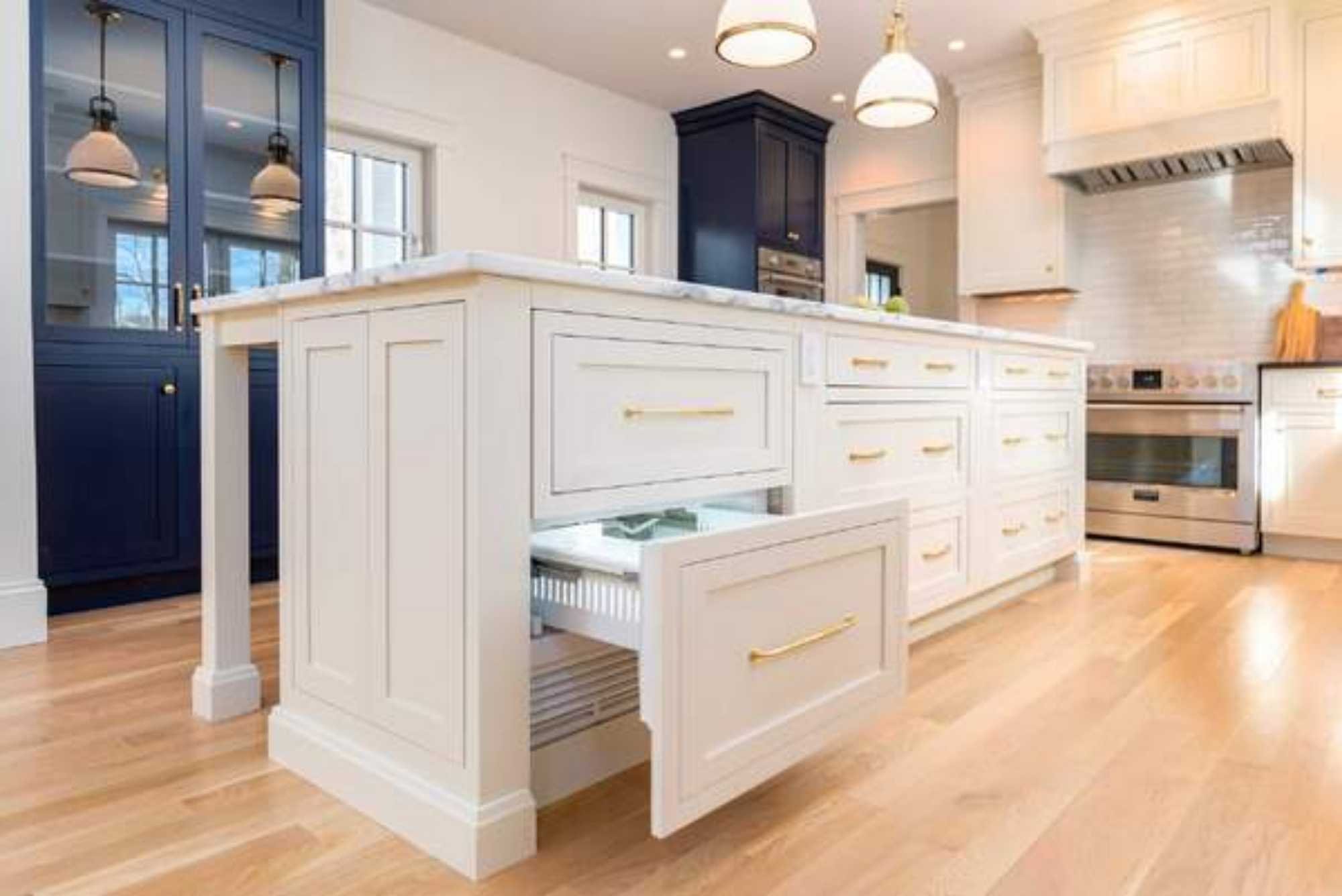 A kitchen remodel featuring a large island with custom drawer storage, built-in cabinets, and hardwood floors by Gilmore Building Co. in Central Massachusetts