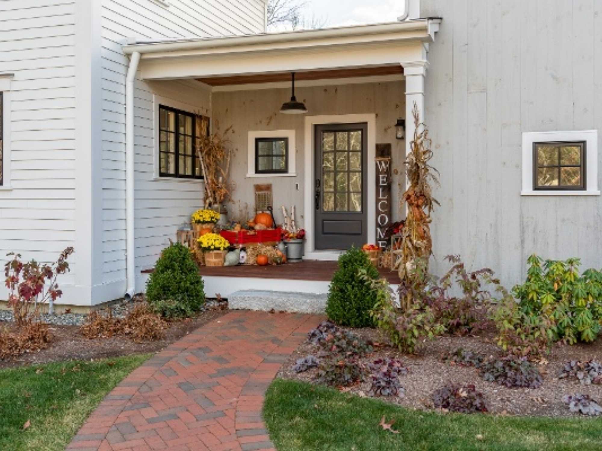 Entrance to a Massachustts home with a small, enclosed front porch, a brick walkway, and landscaping on either side by Gilmore Building Co.