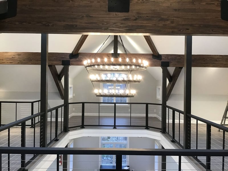 An open second-floor remodel with wooden beams and a custom light fixture by Gilmore Building Co.