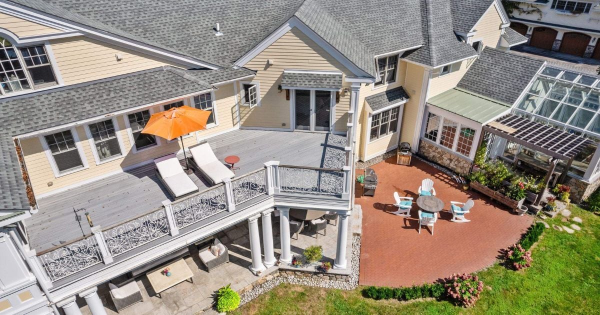 Aerial view of a large remodeled home with an addition, two patios, and a second-story deck by Gilmore Building Co. in Grafton, MA